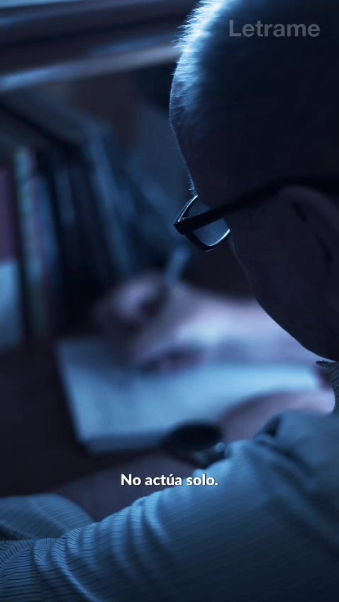 Hombre con anteojos escribiendo de noche